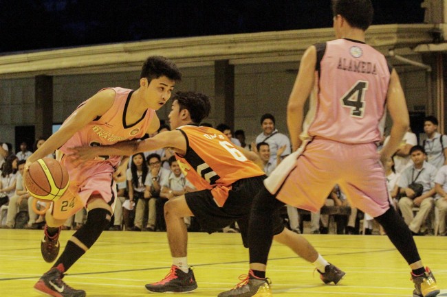A Social Sciences player drives against defenders from the EA Tigers. Photo by Mark Louie Balladares
