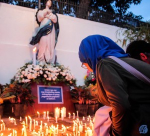 A female Muslim student offering a candle in memory of the Roxas bombing victims. Photo by Camaela Mijares